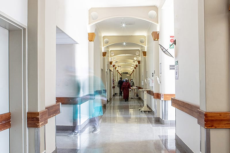 A corridor in the original hospital wing, receding towards a sunlit doorway.