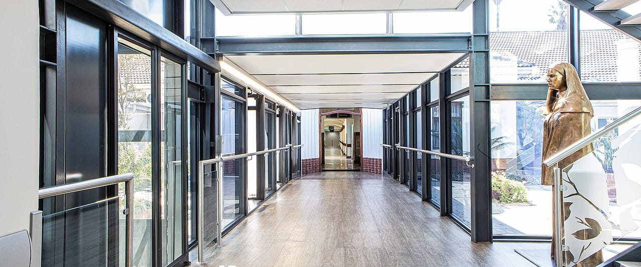 A glazed walkway linking the hospital wings, with the bronze figure of a nursing sister at the far end.