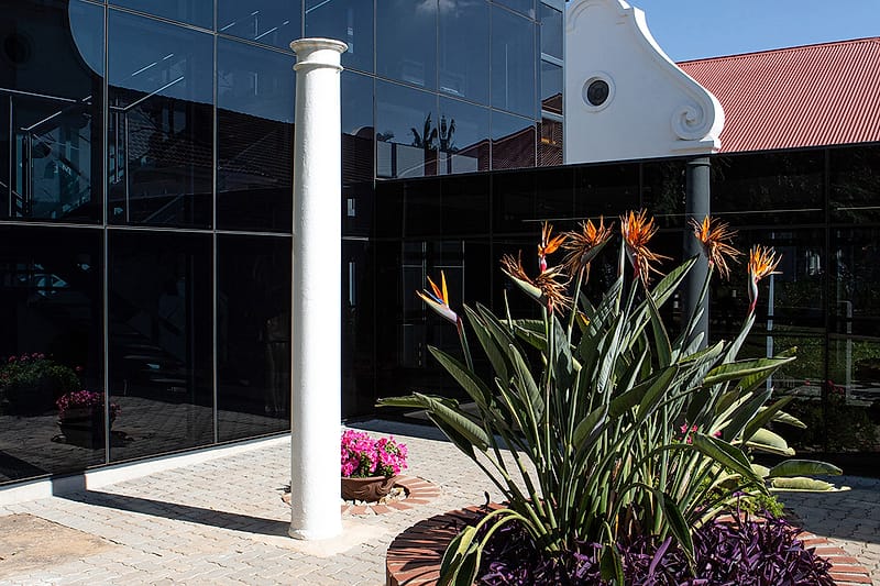 A planted courtyard between the old gabled wing and the glazed newer building.