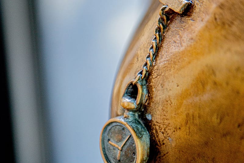 Detail of the bronze nursing sister sculpture — the fob watch pinned at her shoulder.
