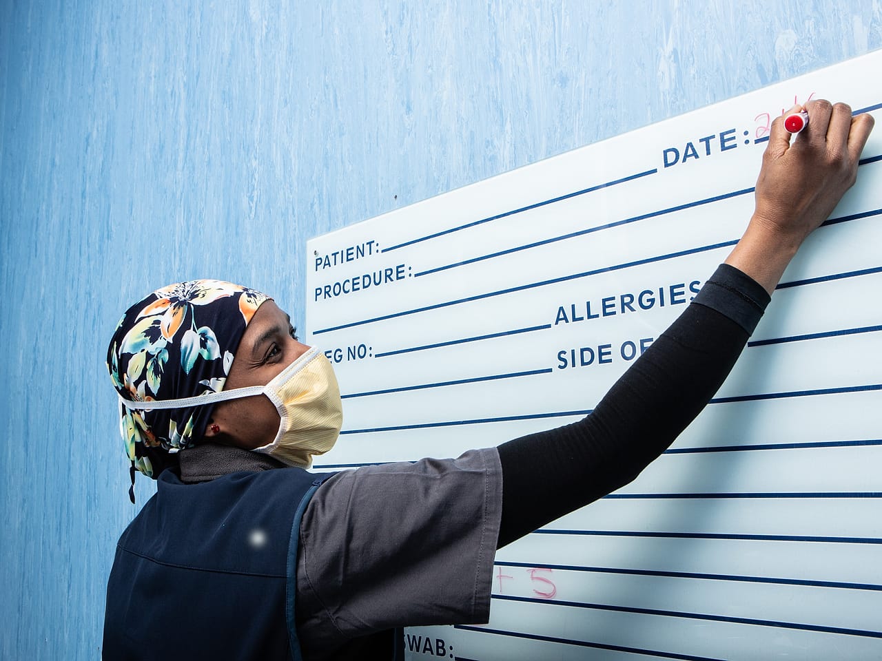 A theatre nurse completing the surgical safety checklist on the theatre whiteboard before a procedure begins.