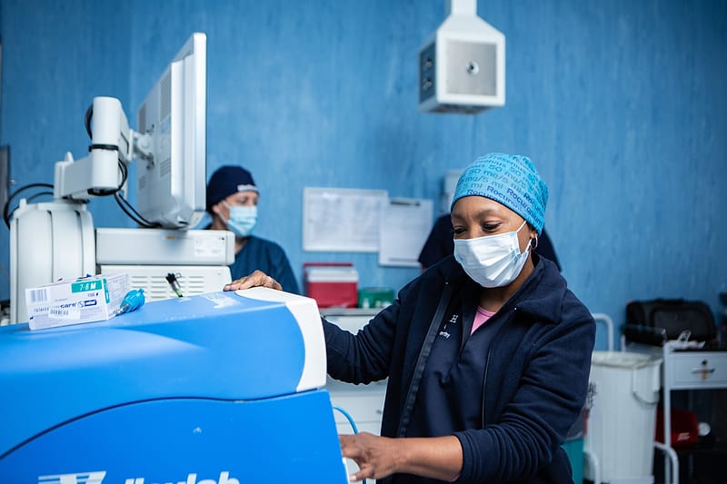 Two theatre staff preparing anaesthetic equipment before a list.