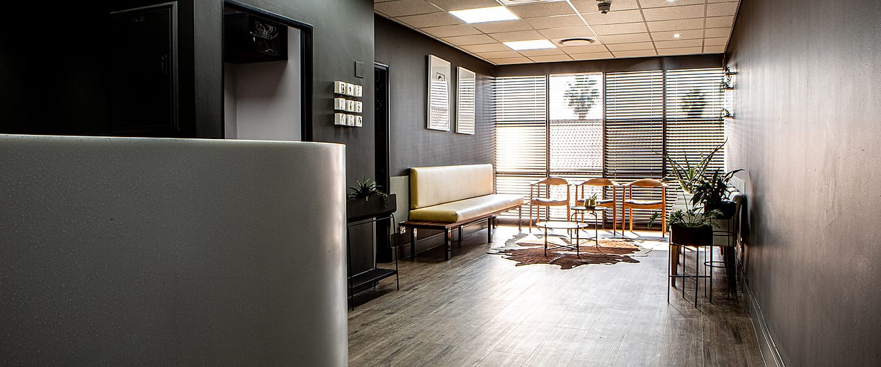 The full waiting room seen from the corridor, benches and chairs along both walls.